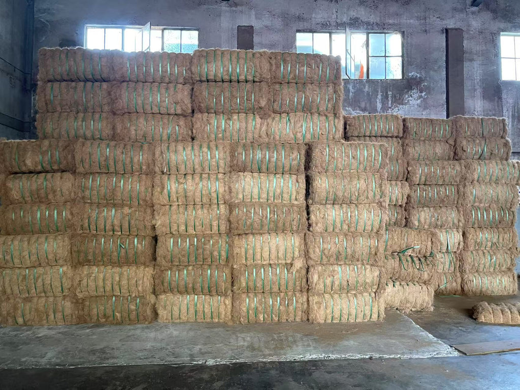 Stacks of baled wheat straw, linen, hemp, wool and bio-mass in a warehouse setting, staging for processing.