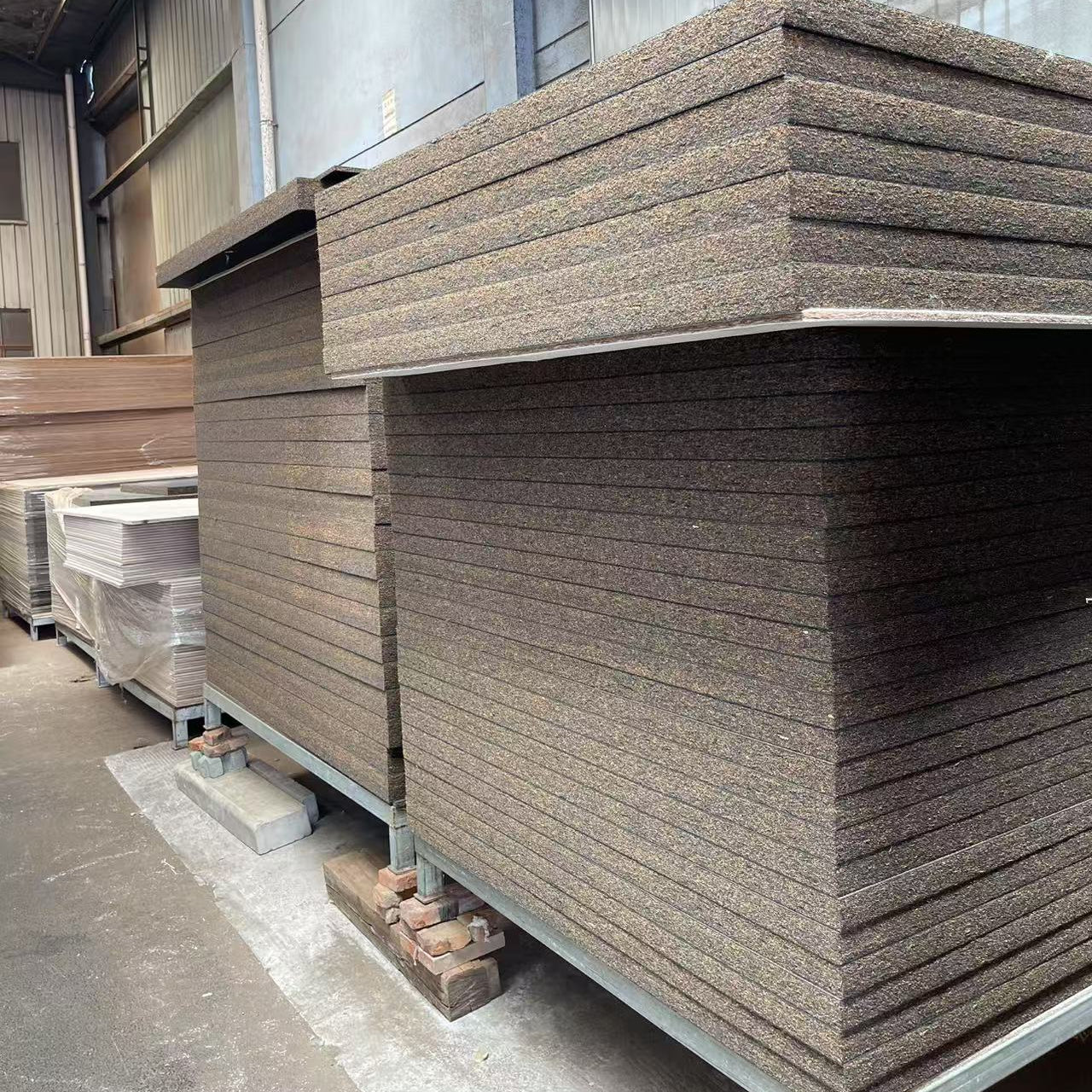Stacks of brown panels on a concrete floor with a warehouse setting.